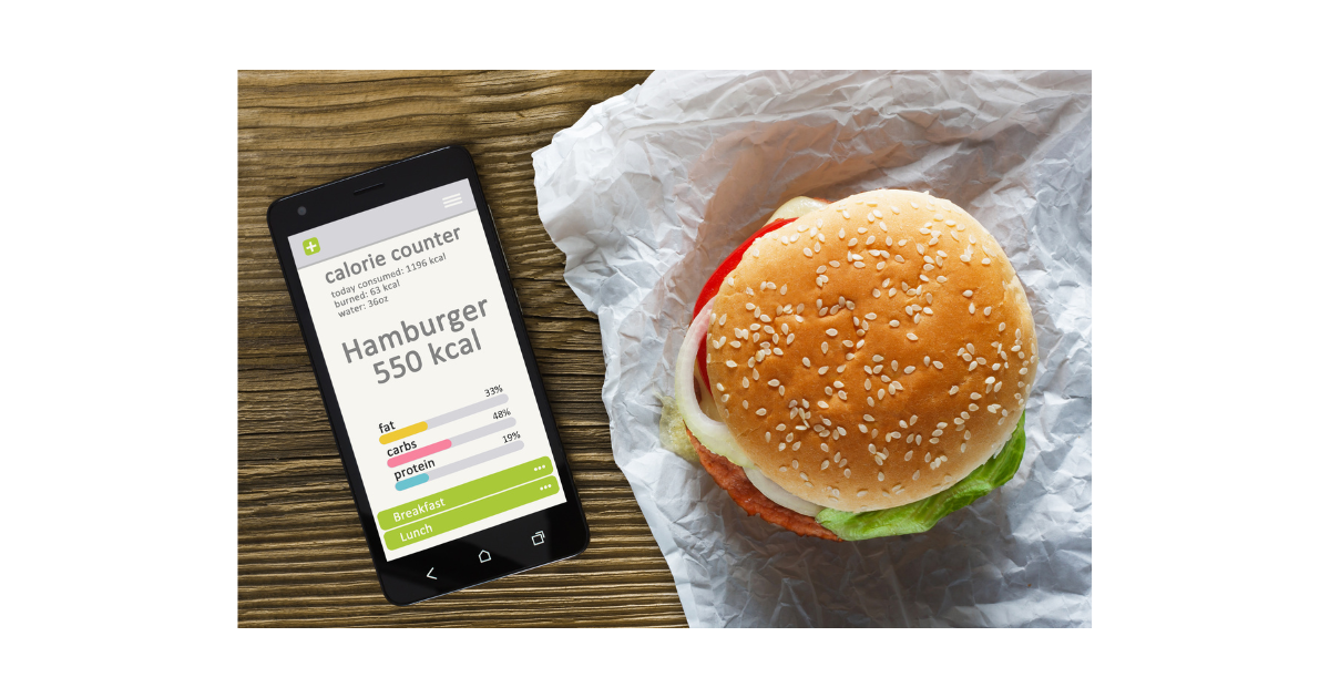 hamburger 550 calories on a table alongside an app on a phone