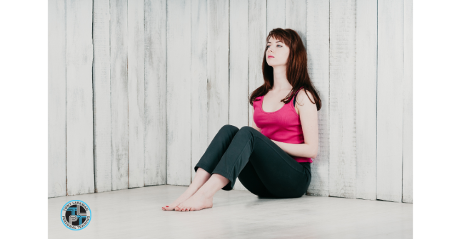 woman sitting on floor, legs bent with back against wall