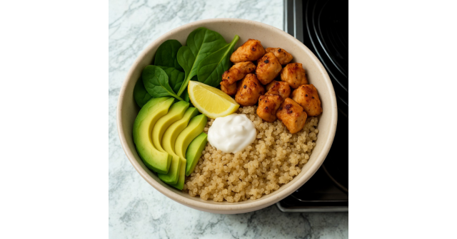Chicken, avocado, quinoa spinach, lemon wedge and blob of yoghurt in a bowl