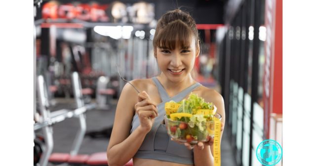Woman holding healthy salad in gym representing nutrition for fat loss