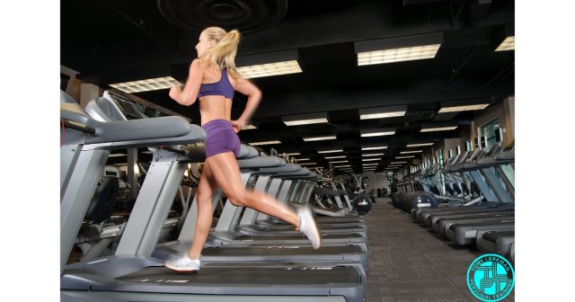 Woman running on treadmill in gym during cardio workout for fat loss