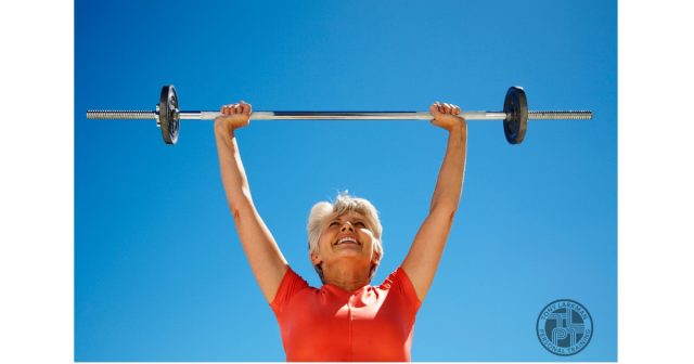 Woman over 50 performing overhead barbell exercise to build muscle and maintain strength with age.