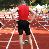older athlete preparing to sprint hurdles in a race on the track