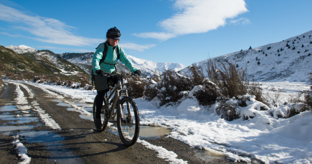 woman on mountain bike on road in wintry conditions