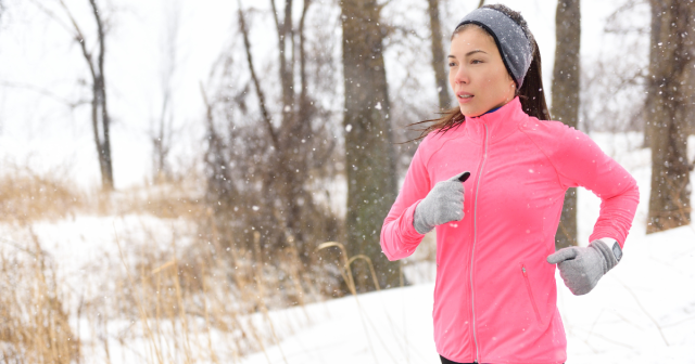 woman gloves hat sweatshirt running in winter snow during her winter workout