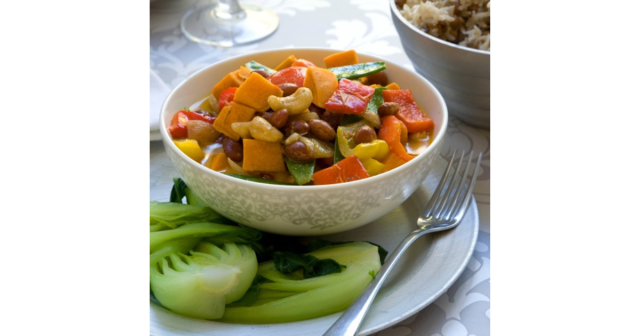 bowl of Thai vegetable curry with kiwi fruit on plate and rice in a bowl