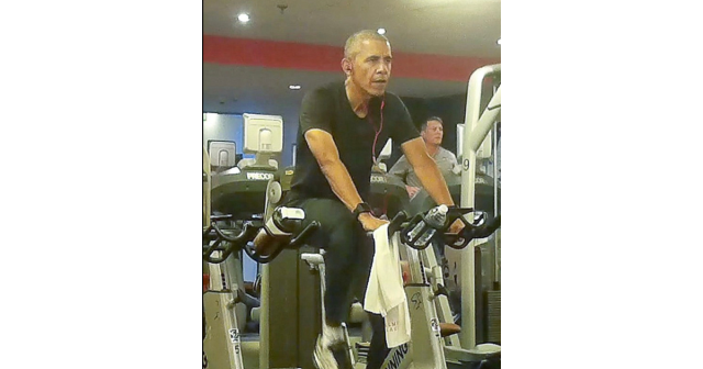Barack Obama on a spin bike in a gym