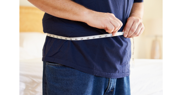 man measuring waist with tape measure