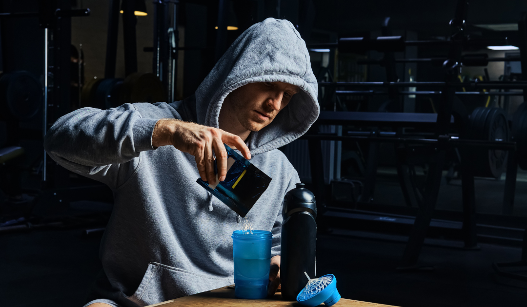 man in hoodie mixing pre-workout powder